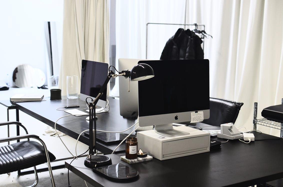 Computers with wires placed on black tables in modern convenient workspace of office