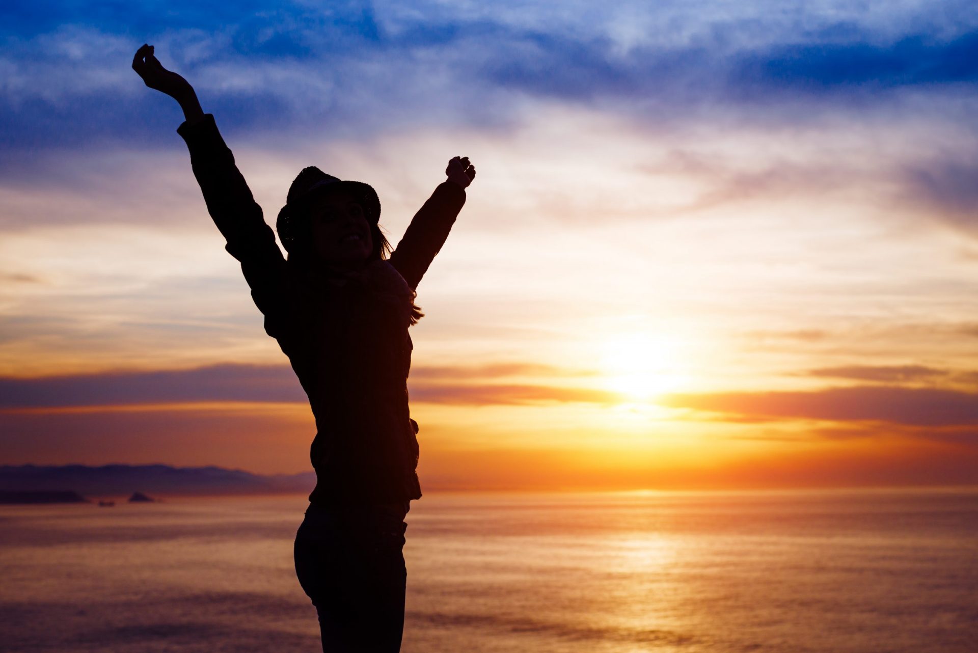 Blissful woman enjoying freedom and happiness on beautiful sunset towards the ocean and sky.
