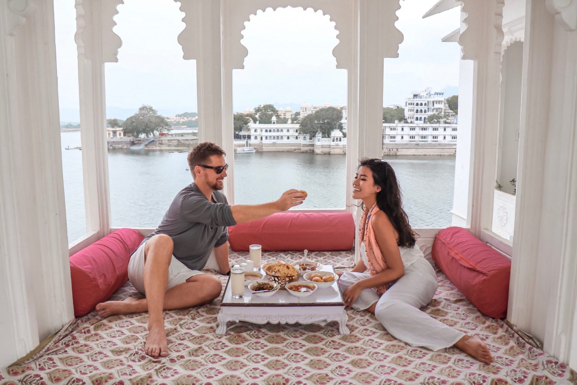 Man and woman sitting on the floor and eating with a view